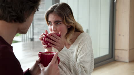 Christmas time, Couple enjoying cozy moment with hot drinks at home, sharing smiles