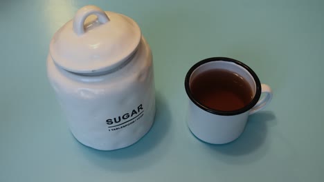 a cup of tea being filled with sugar. sugar is the leading cause of obesity.
