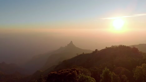 Silhouette-of-mountains-in-the-foreground-with-sun-shining-in-the-sky-after-sunrise