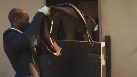 african american man preparing the saddle of the dressage horse