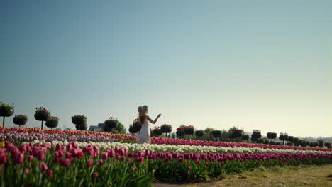 chica corriendo con vista al campo de tulipanes. mujer hermosa sintiéndose libre en las flores.
