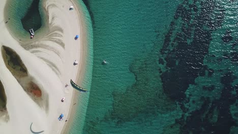 Erhöhender-Schuss-Eines-Kiteboarders,-Der-Den-Drachen-In-Der-Nähe-Des-Strandes-Mit-Kleiner-Bucht-Und-Sonnenschirmen-An-Der-Seite-Fliegt