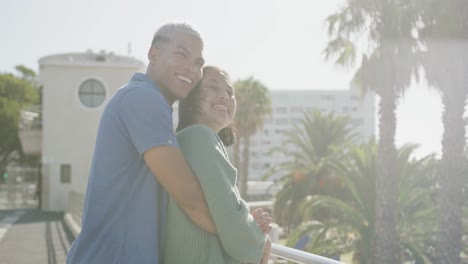 una feliz pareja biracial abrazándose en el paseo marítimo, en cámara lenta