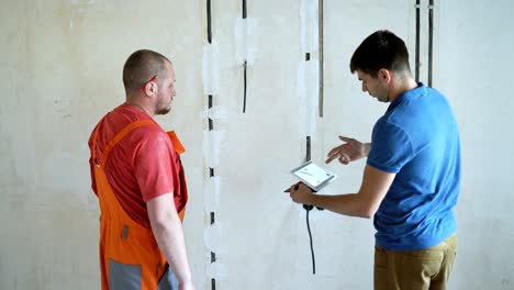 ingeniero y arquitecto discutiendo a través de una tableta inalámbrica digital trabajando en el sitio de construcción interior