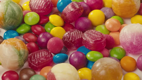 colorful dragee candies, lollipops, bonbons on white background, move in circle, top view close-up. summer bright texture studio shot for store, supermarket. mix of children's sweets made of sugar.