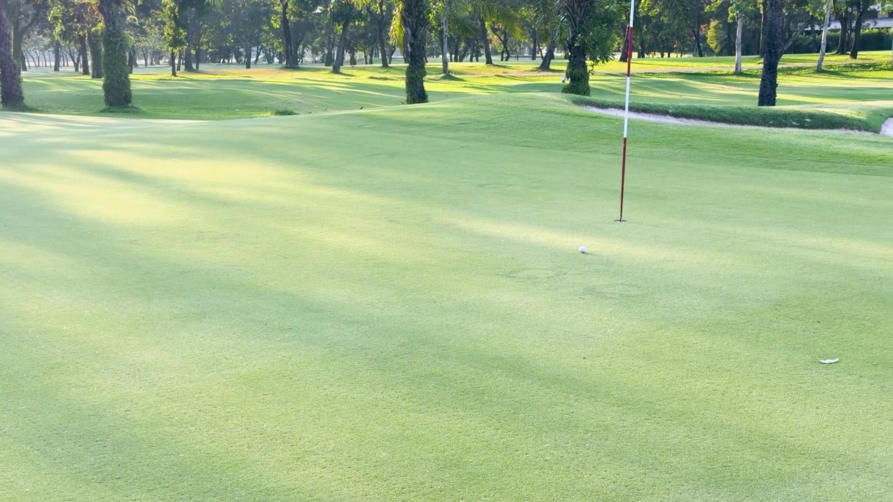 Una pallina da golf bianca rotola su un fairway verde lussureggiante sotto la brillante luce del sole mattutino.