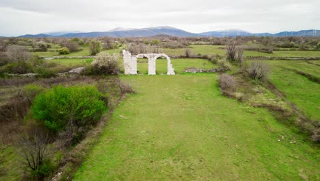 a slow and smooth aerial push towards the stone arches of the ancient ruins of burnum, an archaeological site that used to be a roman legion camp and town near krka national park in dalmatia, croatia