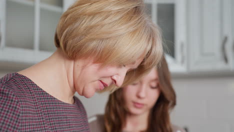 close-up of woman focused on kitchen task while daughter watches attentively, they share a quiet moment of learning and bonding in a modern kitchen
