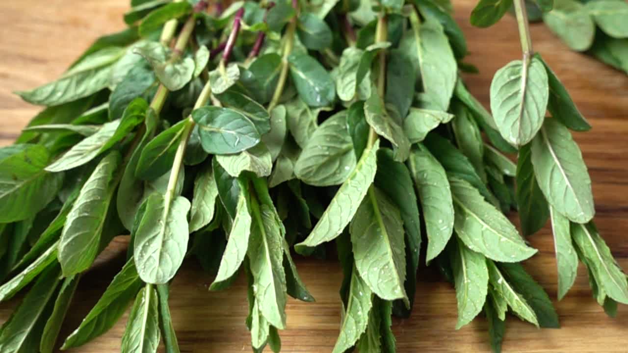 Caduta di foglie di menta su un tagliere. Al rallentatore.
