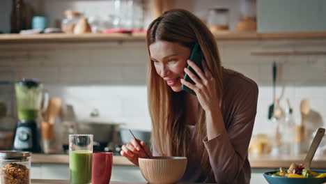 calling girl enjoy breakfast at home kitchen close up. woman talking smartphone