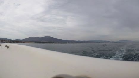 view of coastline mountains from sailing boat stern