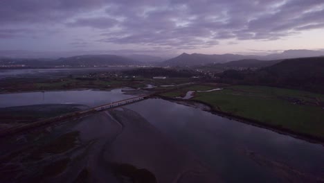 Bridge-crossing-tidal-wetland-habitat,-Dramatic-dusk-landscape-Spain-AERIAL