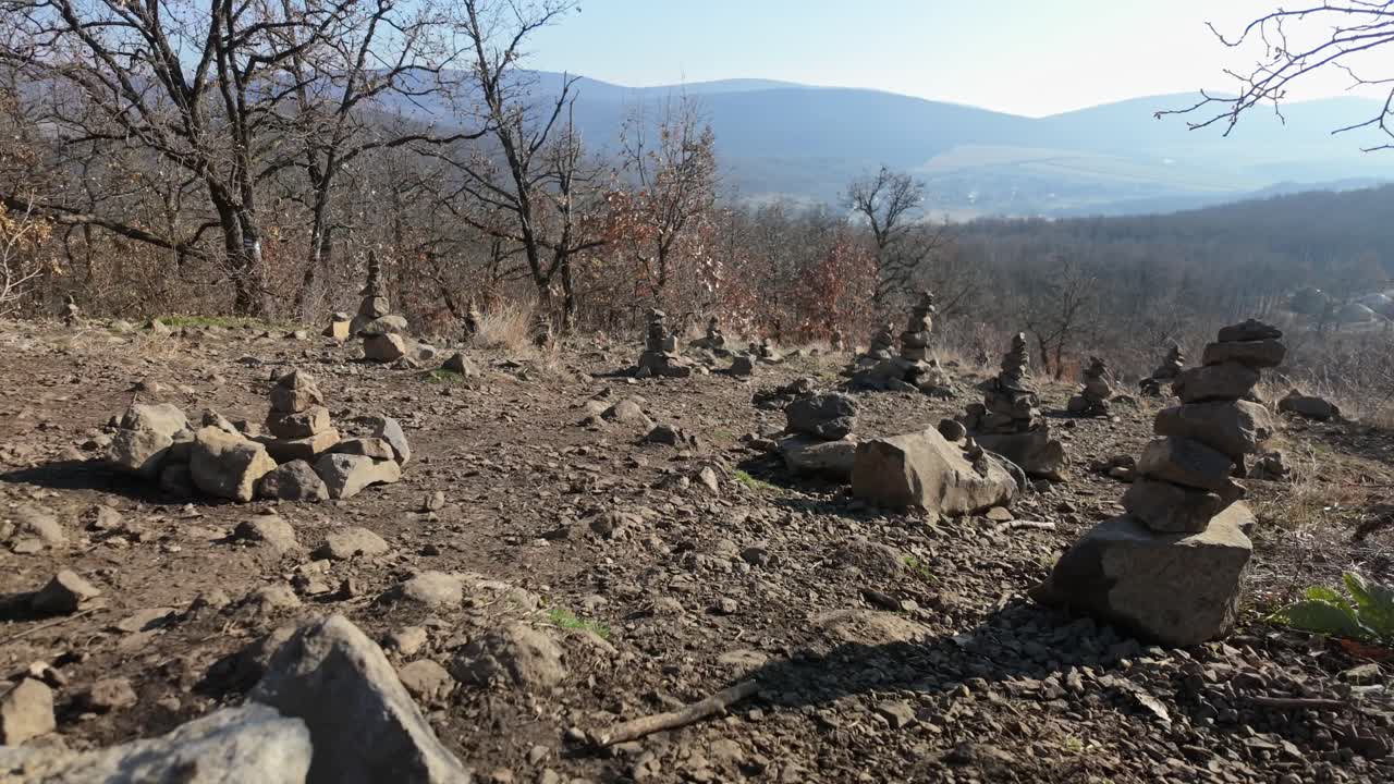 Static shot near Palm of God wooden tourist attraction during the day with handmade balancing rock towers on a hill, near Holloko, Hungary.