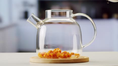 sea buckthorn healthy berries for tea drink, frozen ripe berries in glass jar and branches with leaves top view on dark wooden rustic background, great for skin, heart, vessels and immune system. copy space.