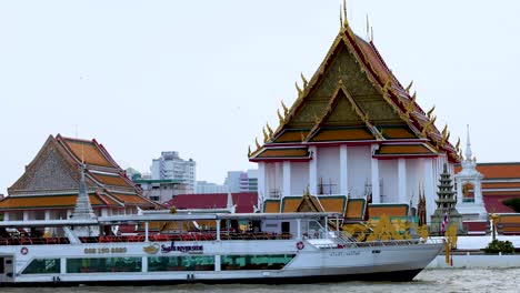 a boat travels past a riverside temple