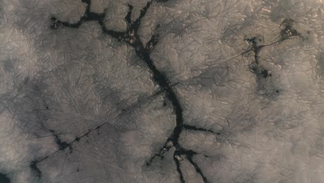 artistic looking cracks in ice sheet across lake ascending aerial