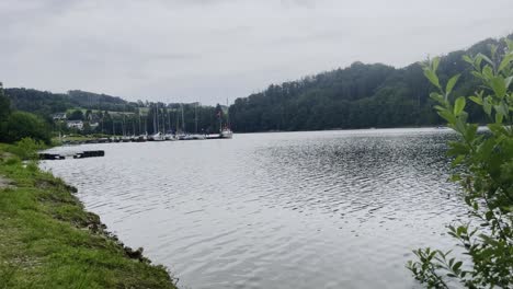 Schiffe-Und-Boote-Liegen-Am-Ufer-Der-Aggertalsperre,-Im-Hintergrund-Ein-Wald