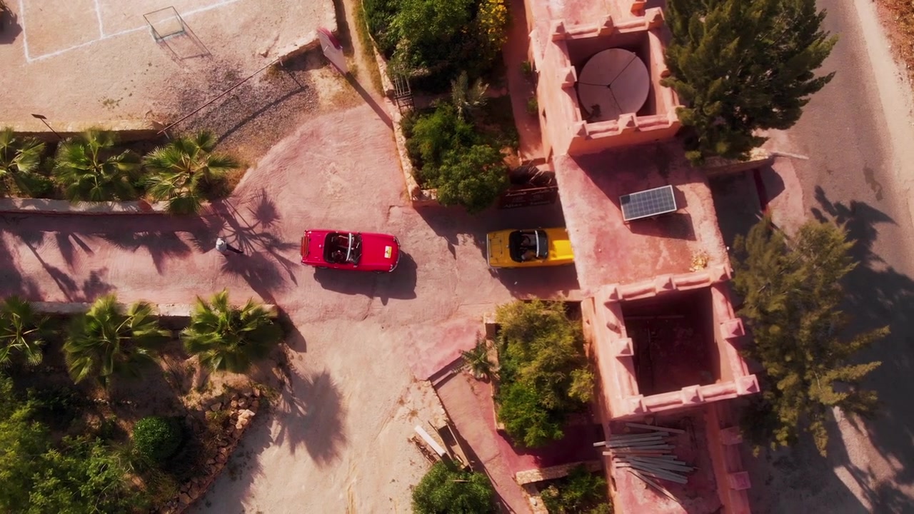 Drone che segue auto decappottabili che lasciano un resort marocchino con vista dall'alto