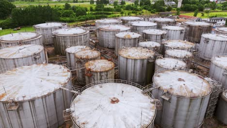 cluster of rusted steel fuel tanks in latvian countryside seen from aerial drone