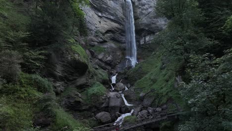 waterfall flows over rocky cliffs surrounded by forest in walenstadt, berschis, switzerland
