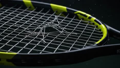 a close-up view of a tennis racket with broken strings, highlighting the intricate details of the string pattern against a dimly lit background