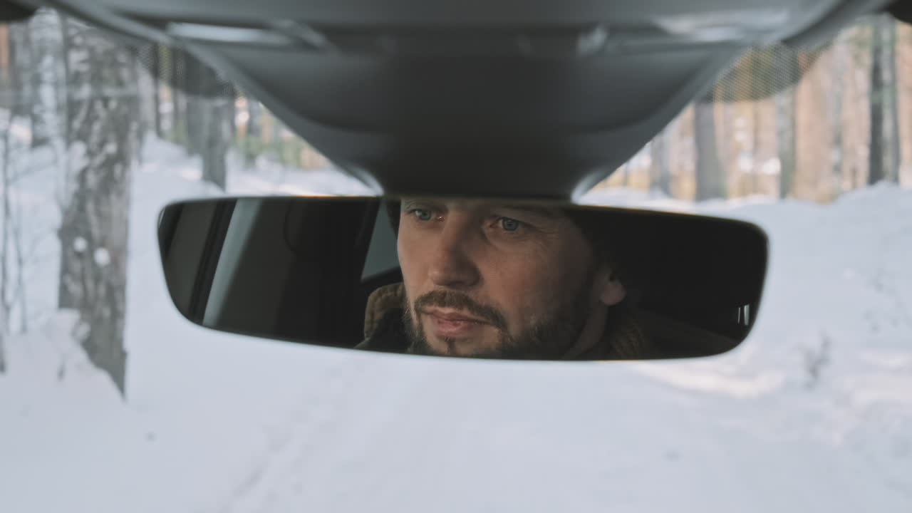 Man in car mirror during winter