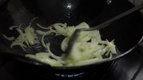 sauteing onions in a chinese metal wok over high heat