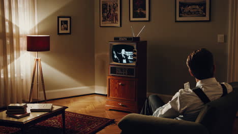 a man watching an old zenith television, using a remote control to view black and white programming