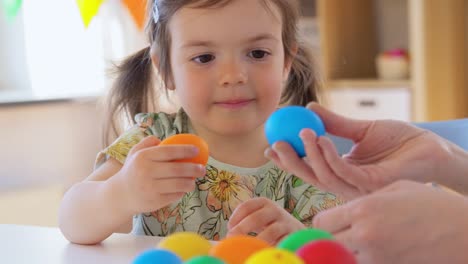 niña y madre golpeando huevos de pascua en casa