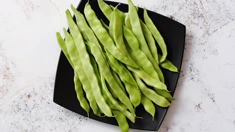 Black-ceramic-plate-with-fresh-green-bean-pods