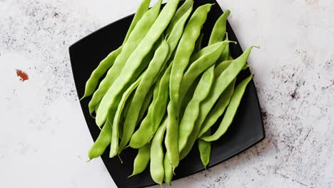 black ceramic plate with fresh green bean pods