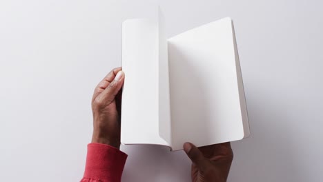 close up of hand leafing through book with copy space on white background in slow motion