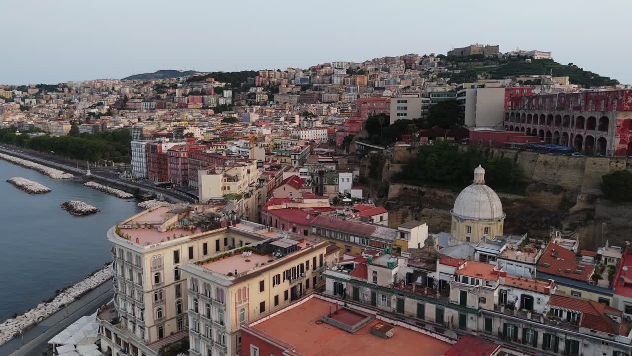 drone take off revealing scenic cityscape of Naples at sunrise with skyline of architectural historical building on the coastline of the sea gulf