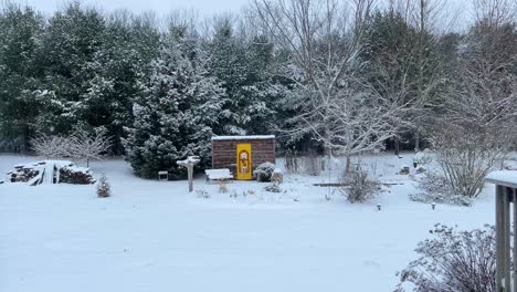 large snowflakes falling in picturesque winter scene after fresh snowfall covers garden and forest in slow motion