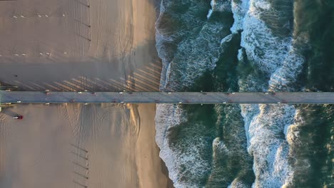 top-down view of pier and beach with sea waves