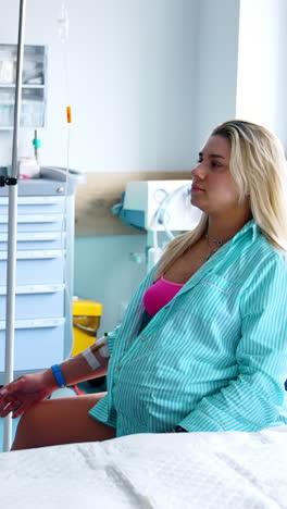 pregnant woman sits on a fitball in the hospital ward. modern medical equipment at backdrop. vertical video
