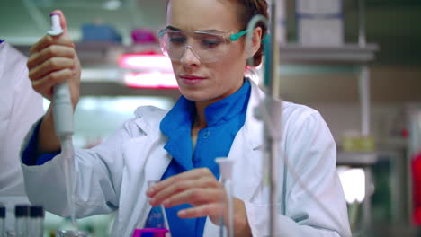 Female-chemist-doing-chemical-experiment.-Chemical-reaction-in-glass-flask