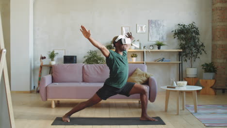 hombre afroamericano con gafas vr practicando yoga en casa