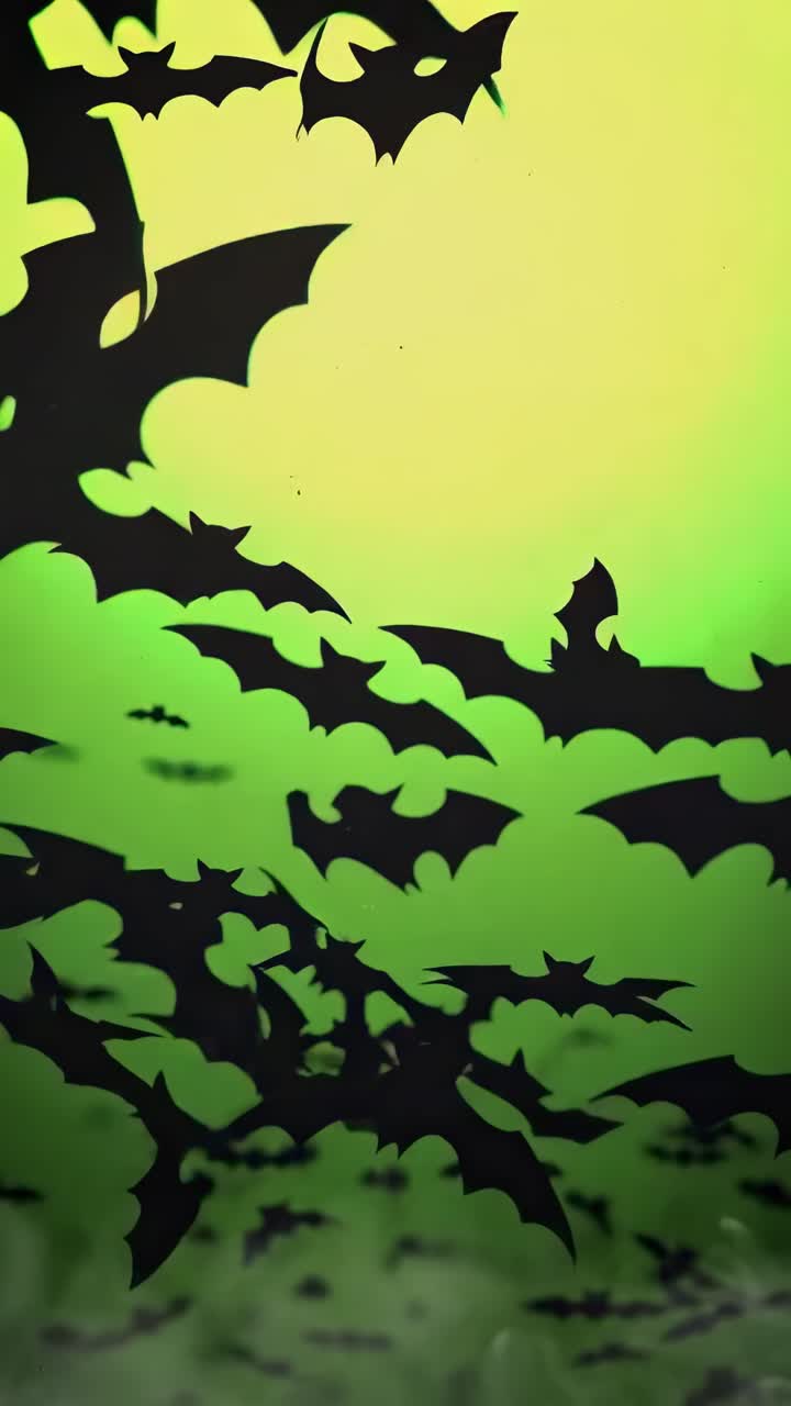 Pipistrelli in silhouette che volano contro un cielo giallo-verde, ripresa dal basso, perfetto per un video spettrale