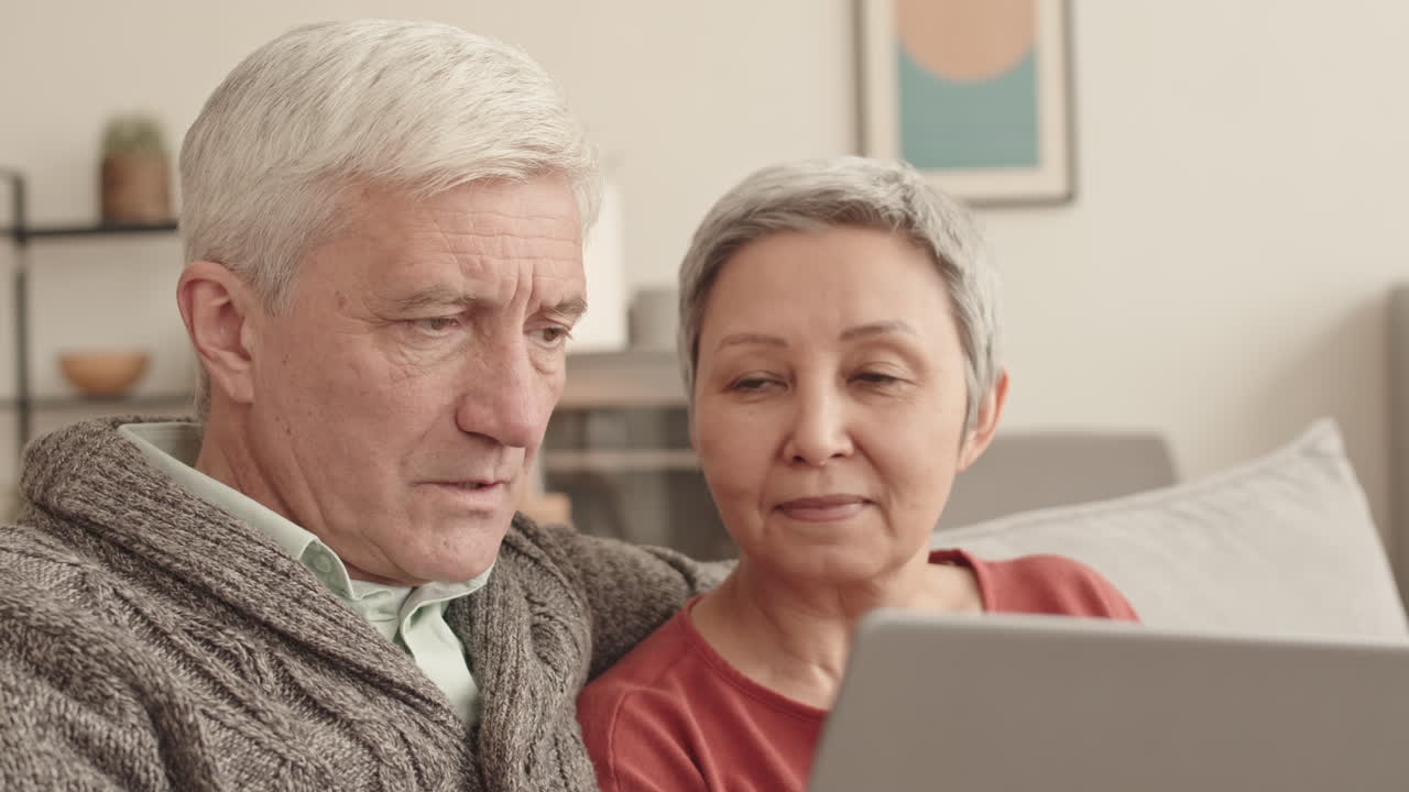 노인 커플이 노트북을 사용하고 있습니다.