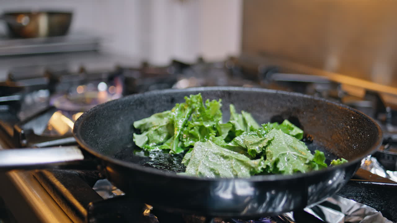 Cook hands preparing greens on frying pan professional kitchen closeup. Man chef