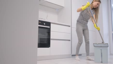 a woman cleans at home she washes the floor with a mop