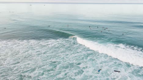 Surfers-on-the-Pacific-ocean-on-a-tropical-island-at-sunrise-and-sunset-waiting-for-waves-and-riding-the-waves-on-their-surfboards