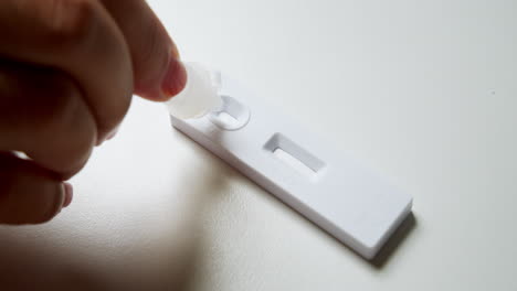 close-up of an individual's hand while testing for possible covid-19 infection, using an antigen test kit