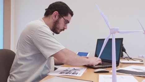man working on laptop with renewable energy models on desk