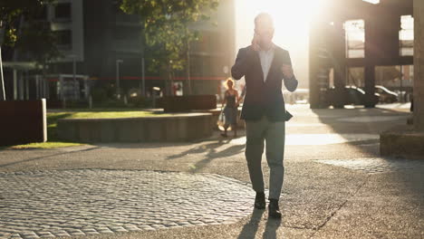 businessman walking and talking on phone in a city