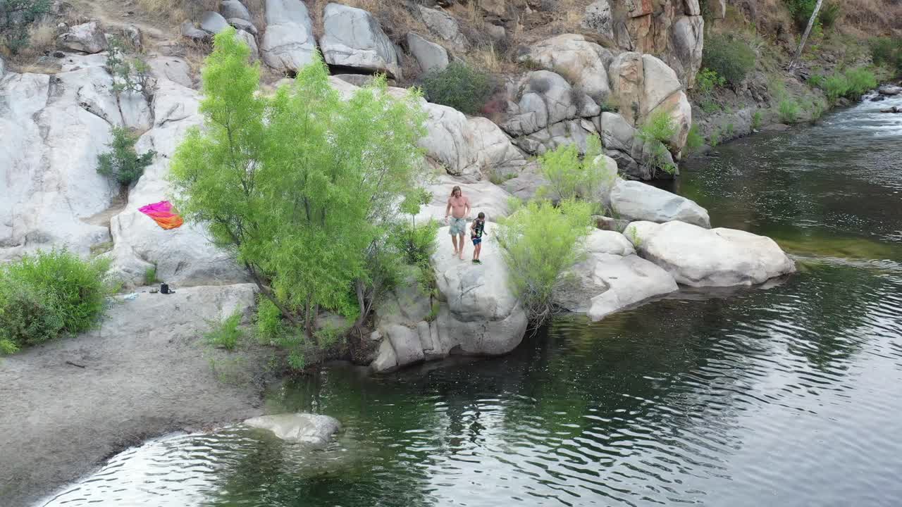 A father and son enjoy cliff jumping off rocks.