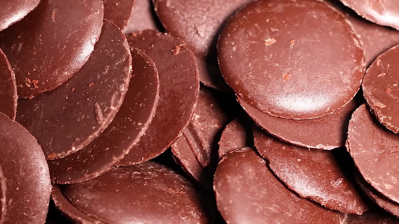 Detailed view of overlapping chocolate discs with a smooth, glossy texture.