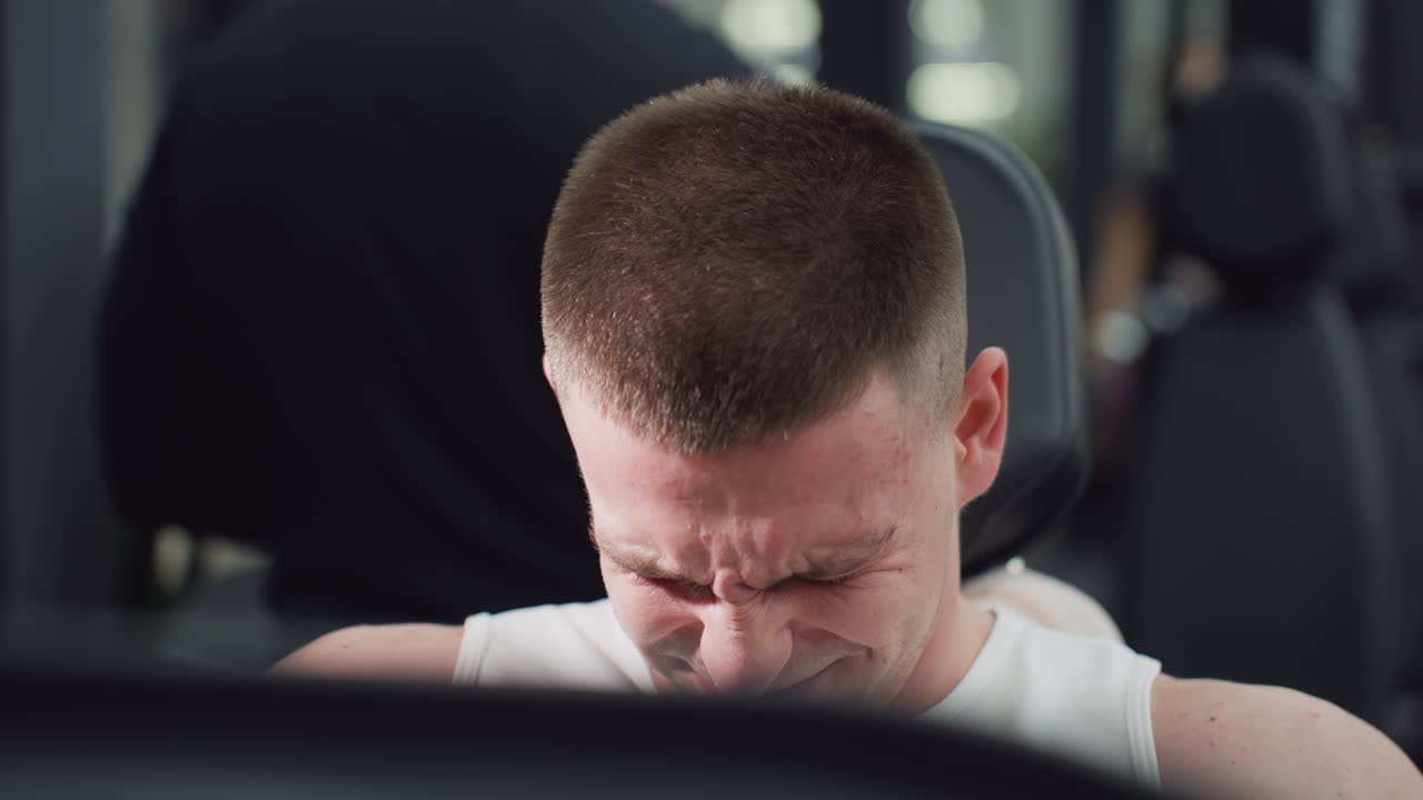 Fitness fanatic facial strain working out on leg press machine demonstrating focused power and controlled motion under intense gym lighting. Tense calves and quads drive strength and endurance