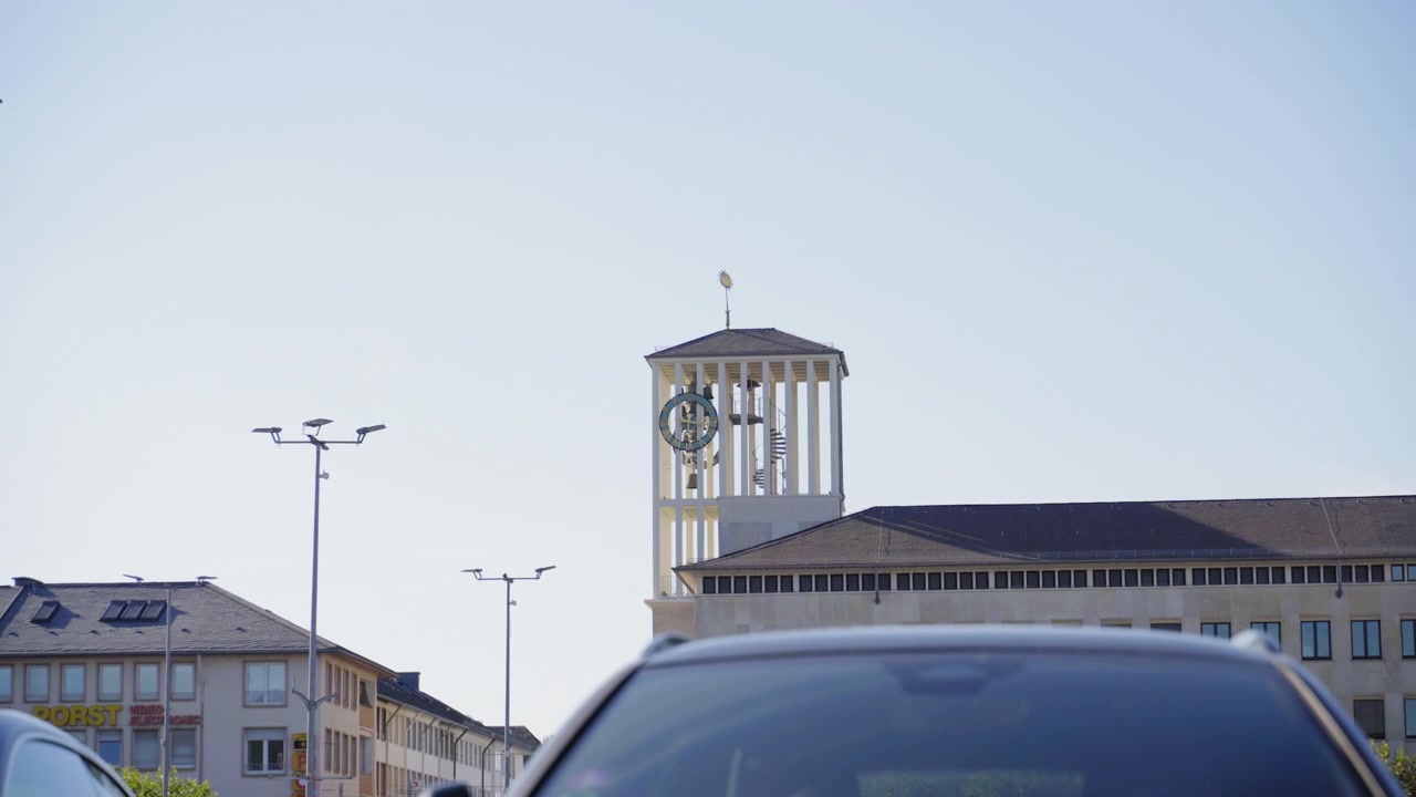 Torre dell'orologio moderna che si erge sopra gli edifici urbani e il traffico cittadino nel centro di Saarlouis, Germania